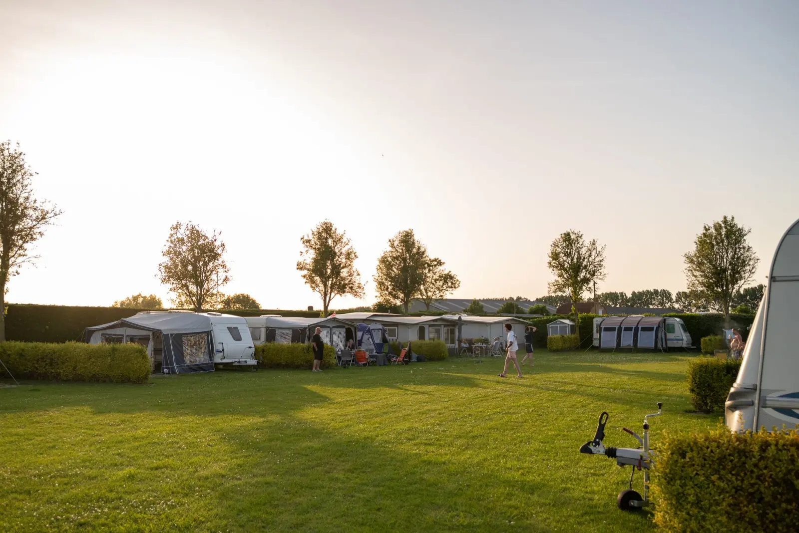 Caravans en tenten op het ruime kampeerveld in de avondzon — Het Platte Putje