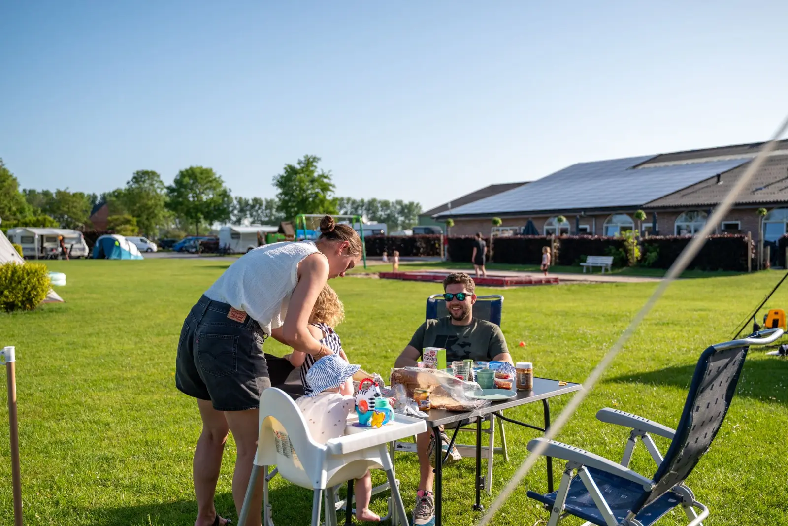 Gezin ontbijt gezellig aan tafel op de kampeerplaats — Het Platte Putje
