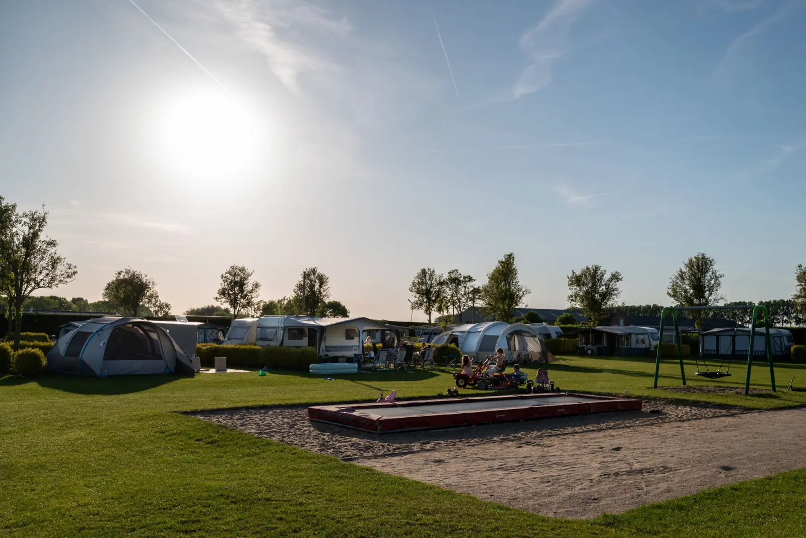 Ruime kampeerplaatsen met speeltuin in de avondzon — Het Platte Putje