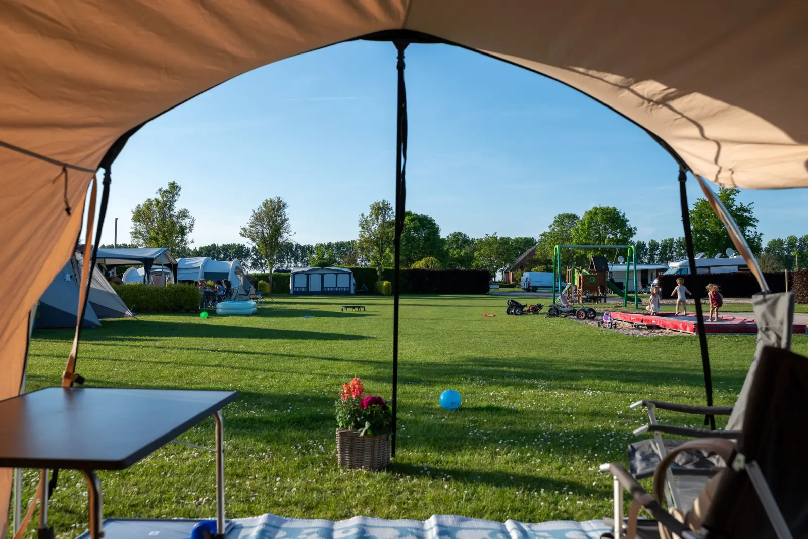 Uitzicht vanuit de tent over het kampeerveld en de speeltuin — Het Platte Putje